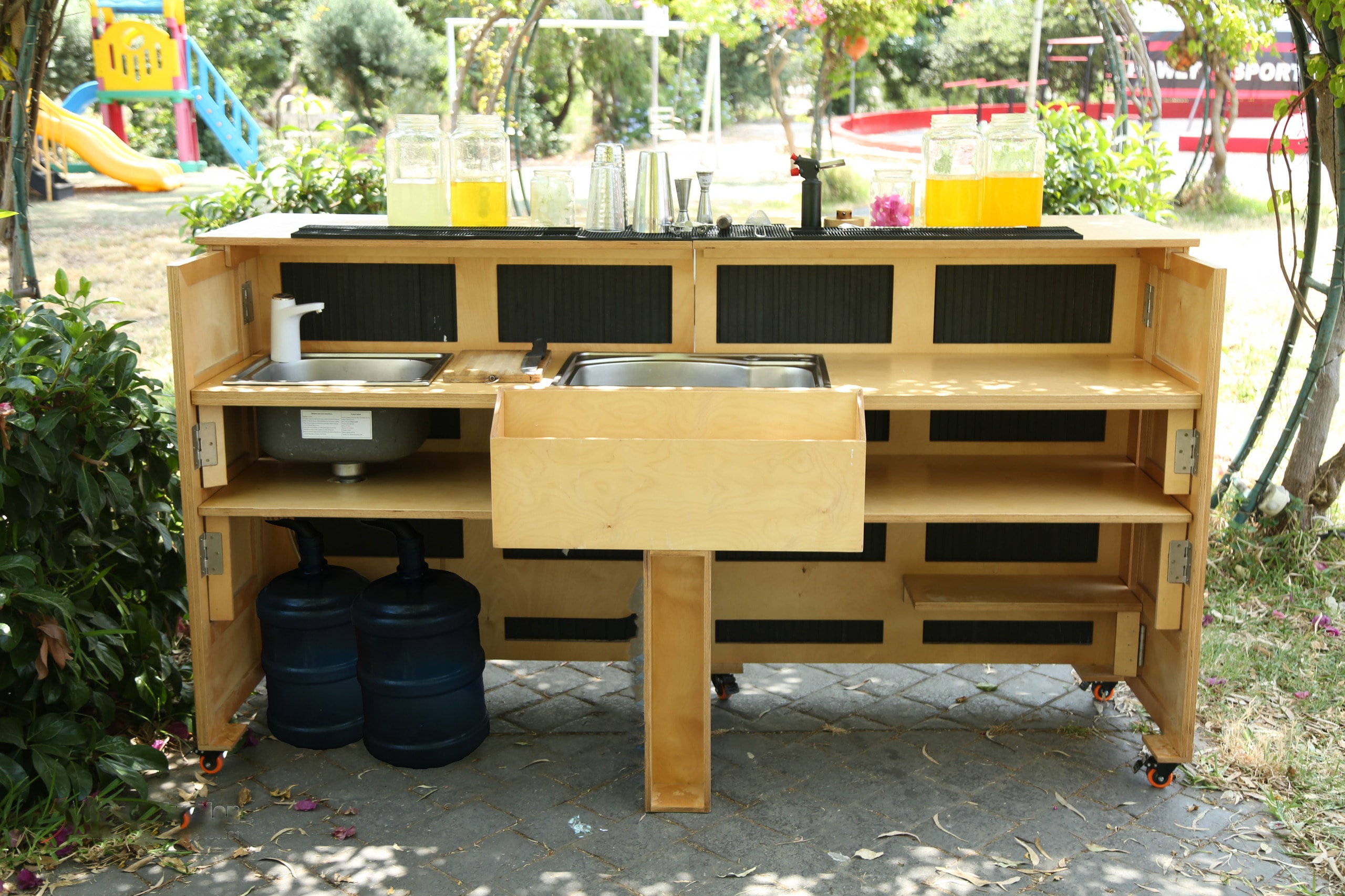 Rear view of the Kaizen Station bar showing the built-in sink, ice bin, internal shelves, and water tanks